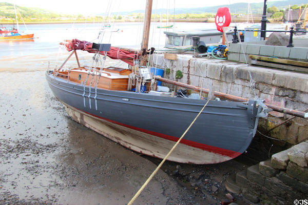 Boat moored at Conwy harbor with stone steps leading up to quay. Conwy, Wales.