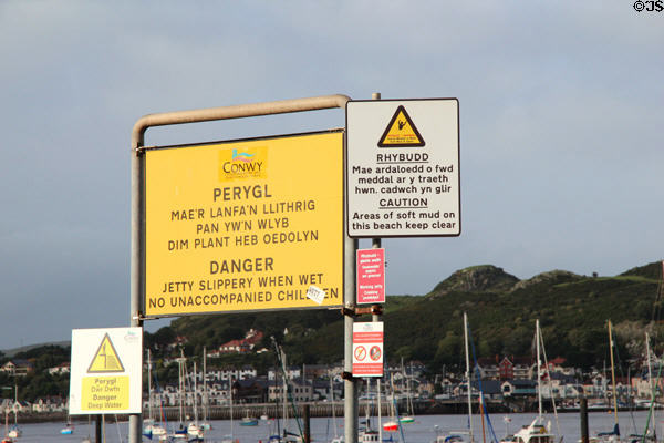 Warning signs in Welsh & English along harbor promenade. Conwy, Wales.