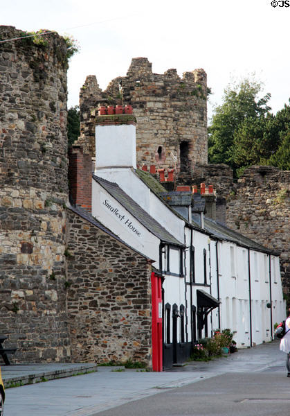 The Smallest House in Great Britain, painted red, said to have been built to fill in a gap between the adjacent row houses and city wall. Conwy, Wales.