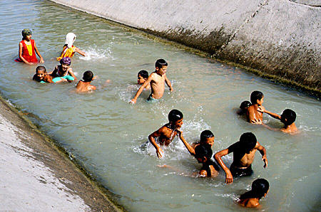 Children cool off in a ditch in Bukhara. Uzbekistan.