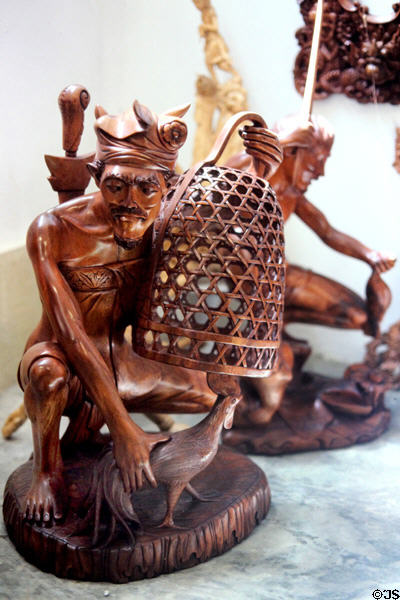 Carving of man with fighting cock & typical basket. Bali, Indonesia.