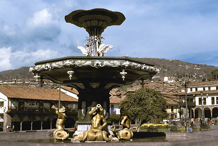 Triton fountain in Plaza de Armas with hills of Cusco. Peru.