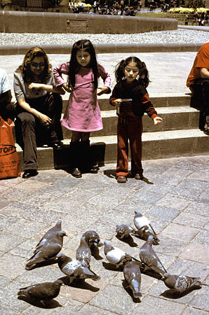 Children feeding pigeons in Plaza de Armas, Cusco. Peru.