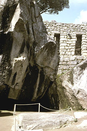 Machu Picchu Condor Temple with wing-shaped cliffs, cave, & sacrificial stone on ground. Peru.