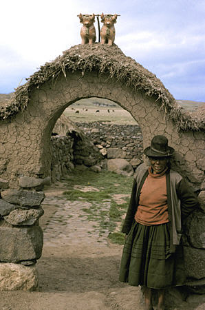 Farm woman in front of gate with two bulls (for luck) near Puno. Peru.