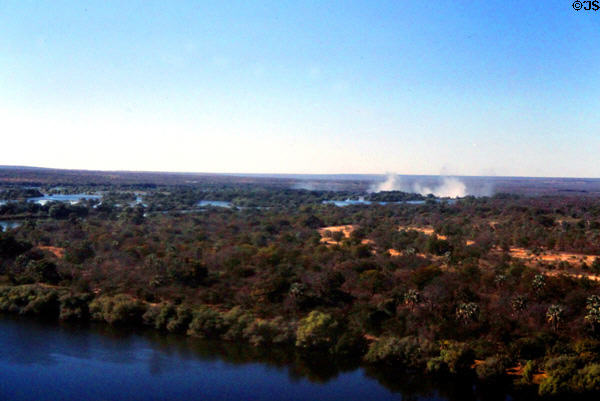 Zambezi River surrounded by jungle with mist of Victoria Falls beyond. Zimbabwe.