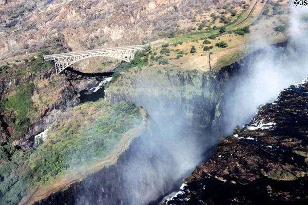 Mist rises from Victoria Falls with bridge in background. Zimbabwe.