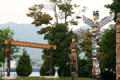 Northwest coast native totem poles in Stanley Park against mountains. Vancouver, BC.