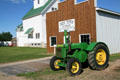 Antique rubber-tired John Deere D tractor in front of Myhr & Wallace Implements board & batten building at Doc's Town. Swift Current, SK