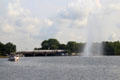 Water spout fountain with passenger train crossing bridge between inner & outer Alster. Hamburg, Germany.