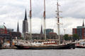 Morgenster, a 48m, two masted tall ship profiled against city. Hamburg, Germany.