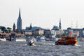Passenger ferry crossing harbor with towers of Hamburg in background. Hamburg, Germany.
