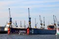 Elbe River shipyard with floating drydock & cranes. Hamburg, Germany.