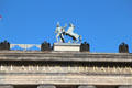 Statue of Greek-style figure & horse plus eagles atop Altes Museum Berlin. Berlin, Germany.