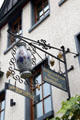 Wrought iron sign on wine shop with hanging grapes & ceramic wine jug. Bacharach, Germany.