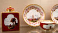 Meissen porcelain red tea service & plate with Baroque border with Watteau & trade travel scenes painted in white quatrefoil at Meissen porcelain museum at Lustheim Palace. Munich, Germany.