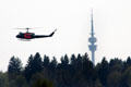 Helicopter flying at Flugwerft Schleissheim with TV tower in distance. Munich, Germany.