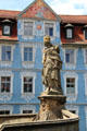 Empress Kunigund statue against blue Baroque building across river from Bamberg Old Town Hall. Bamberg, Germany.