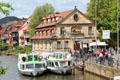 Tour boats docked on Regnitz River beside antique crane & buildings of Little Venice shore. Bamberg, Germany.
