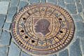 Coburg city shield on street manhole cover surrounded by cobblestones. Coburg, Germany.