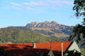 Building with red tiled roof with mountain cliffs in background in Chiemsee region. Chiemsee, Germany.