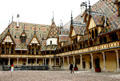 Courtyard of Hotel Dieu with colored glazed tile roof, gables & finials. Beaune, France.