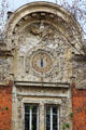 Clock on facade under carved arch in Le Marais. Paris, France.