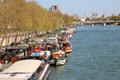 Triple parking houseboats near Passerelle Léopold-Sédar-Senghor footbridge over Seine. France.