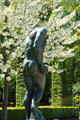 Bronze sculpture by Auguste Rodin with fruit tree blossoms at Rodin Museum Garden. Paris, France.