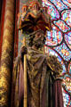 Carving of painted Saint carrying staff & round cross with Evangelist symbols on Gothic column at St Chapelle. Paris, France.