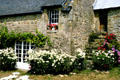 Flower display in front of Brittany stone dwelling with slate roof. Carnac, France.