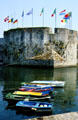 Flag topped stone town wall & small boats. Concarneau, France.