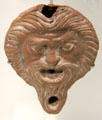 Roman terracotta oil lamp with theater mask of satyr at Musée de la Romanité. Nimes, France