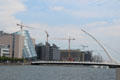 Dublin Convention Center with leaning glass cylinder beside Samuel Beckett Bridge over River Liffey. Dublin, Ireland.