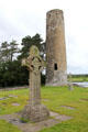 O'Rourke's Round tower with replica Cross of Scriptures at Clonmacnoise. Ireland.