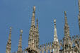 Carved figures stand atop Duomo spires. Milan, Italy.