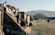 People sunning on ancient walls at Teotihuacán with Pyramid of Moon beyond. Mexico.