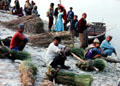 Reed gatherers wait for boats on river bank in Chitwan National Park. Nepal.