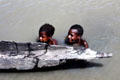Children swimming in the water near a canoe in Tambanam. Papua New Guinea
