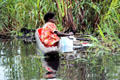 Woman washing her clothes from a canoe in Kambaramba. Papua New Guinea.