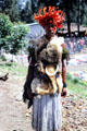 Woman with colorful feathered headdress & tree kangaroo fur in a highland market. Papua New Guinea.
