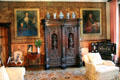 Carved cabinet flanked by portraits in Queen Mother sitting area at Glamis Castle. Angus, Scotland.