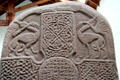 Pictish cross-slab detail of entwined animals with beaks touching above lacey cross at Meigle Sculptured Stone Museum. Meigle, Scotland.
