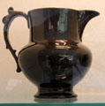 Black glazed earthenware jug with shaped handle at Coalport China Museum. Ironbridge, England.