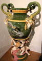 Earthenware scroll-handled vase sculpted with goats, exotic birds & supported by cupids by Albert Ernest Carrier de Belleuse for Minton of Stoke-upon-Trent at Potteries Museum & Art Gallery. Hanley, Stoke-on-Trent, England.