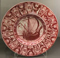 Ruby lustre plate with galleon ringed by symbolic winds by William De Morgan at Ashmolean Museum. Oxford, England.
