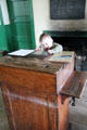 Visiting student sits at teacher's desk in Ballydown National School at Ulster Folk Park. Belfast, Northern Ireland.