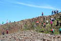Visitors climb the hexagonal blocks of Giant's Causeway. Northern Ireland