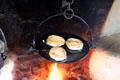 Griddle cakes on andiron over fire in Mellon Homestead at Ulster American Folk Park. Omagh, Northern Ireland.