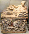 Etruscan carved alabaster cinerary urn with reclining man on lid & battle panel on chest from Chiusi at British Museum. London, United Kingdom.